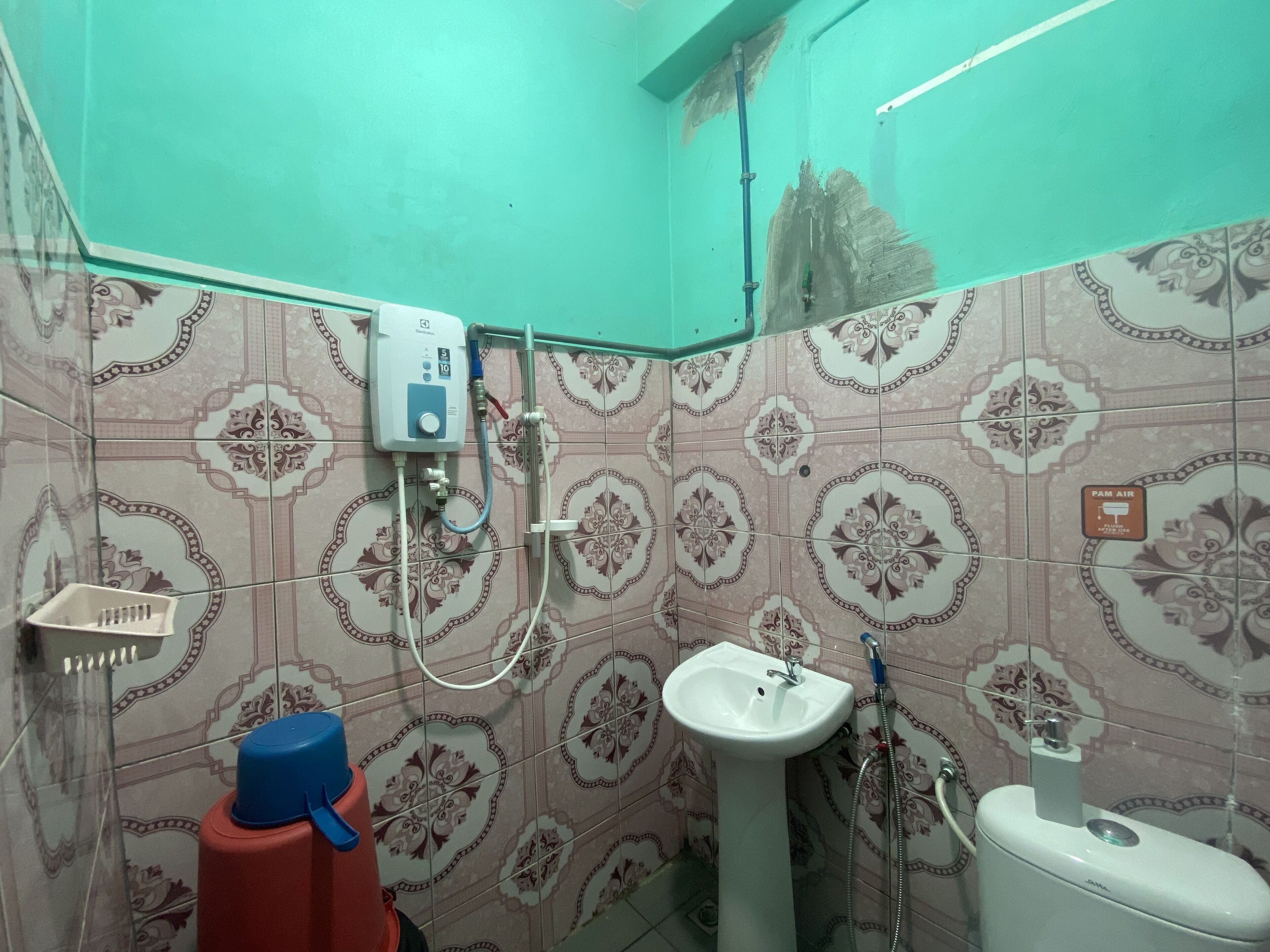 A bathroom with patterned tiles, a pedestal sink, a toilet, and a shower unit.