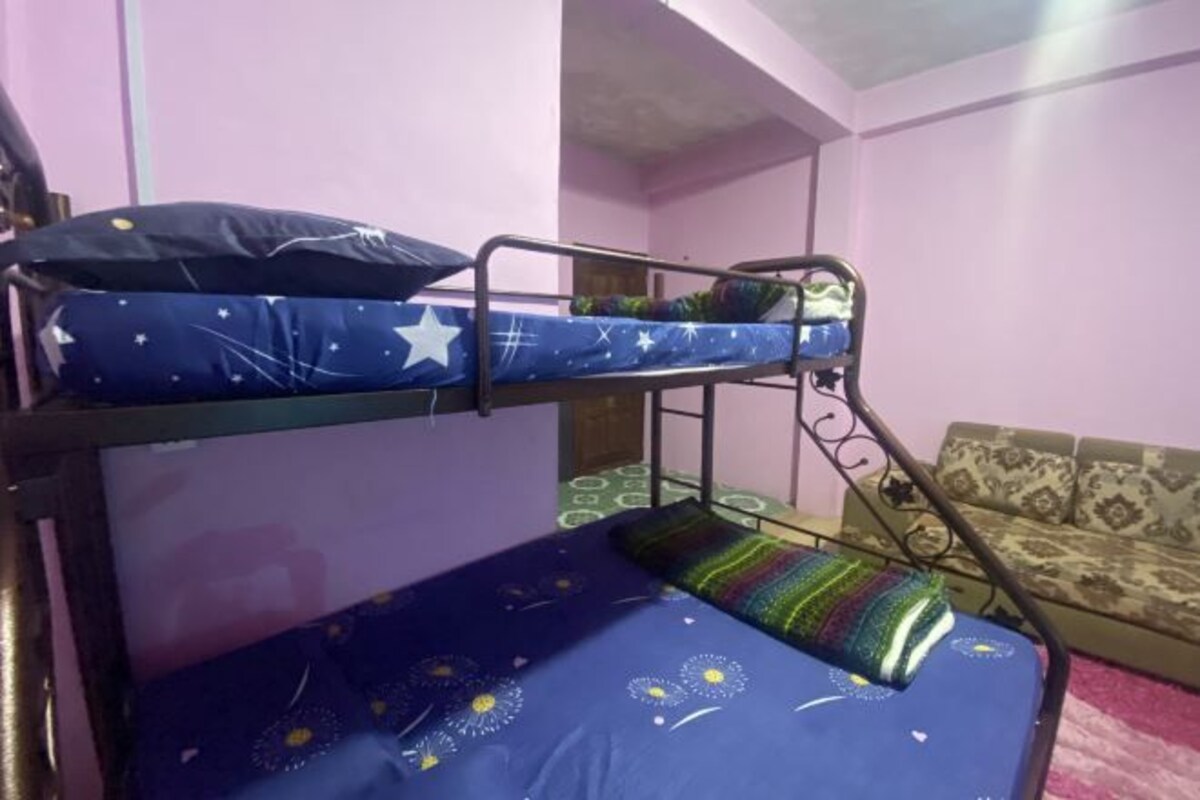 A bunk bed with a star-patterned blue mattress and a green and white striped pillow.