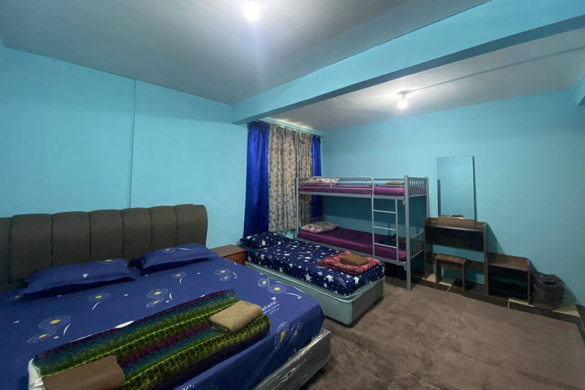 A bedroom with a bunk bed, a single bed, a desk, and a mirror.