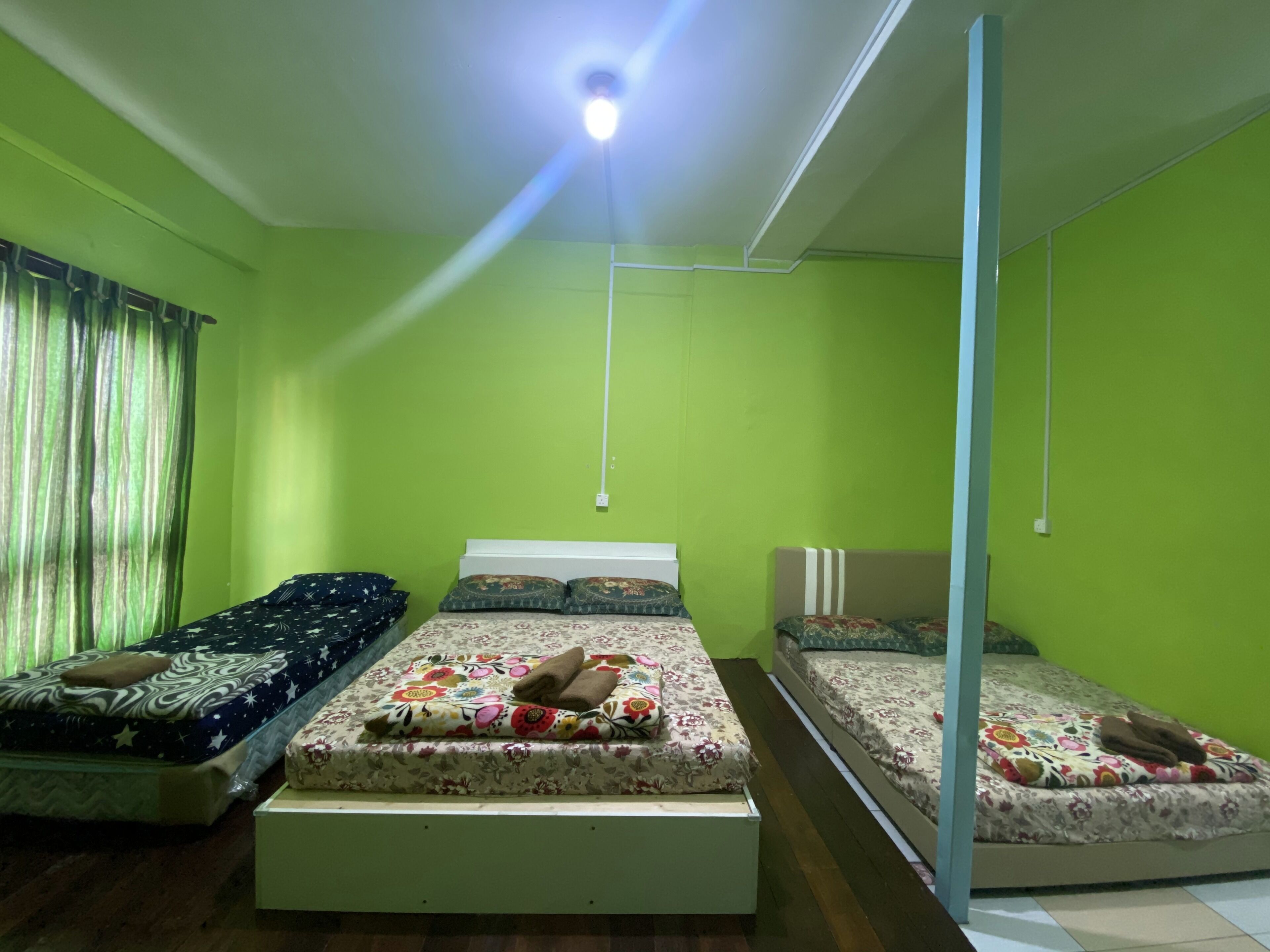 A room with three beds arranged in a row, each with different bedding patterns.