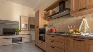 A modern kitchen with wooden cabinets, a built-in oven, a stove, and a TV. - Manzoni Apartment (Roseto degli Abruzzi)