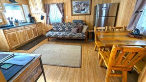 A compact kitchen with wooden cabinets, a sofa, a dining table with chairs, and a refrigerator. - Yellowstone's Treasure Cabin #6, few min drive from Yellowstone Park (Gardiner)