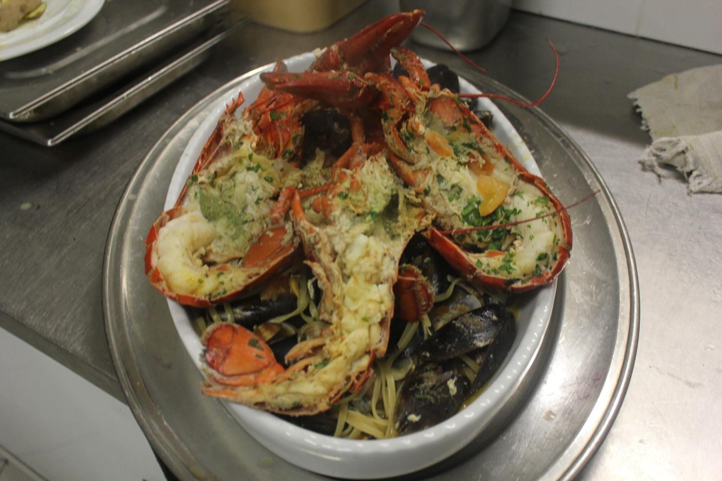 A seafood dish with mussels and lobster on a white plate.