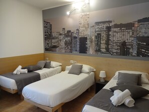 A hotel room with two single beds, a cityscape mural on the wall, and a nightstand with a lamp. - Hotel Nuova Orchidea (Dresano)