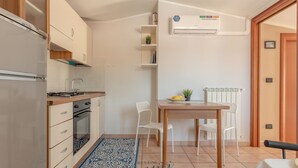 A compact kitchen with a refrigerator, stove, oven, and a dining area with a table and chairs.