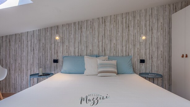 A modern bedroom with a large bed, two bedside tables, and a skylight above.