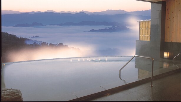 A serene indoor infinity pool with a view of mist-covered mountains. - Matsudai Shibatoge Onsen Unkai (Tokamachi)