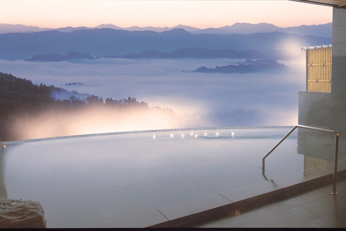 A serene indoor infinity pool with a view of mist-covered mountains.