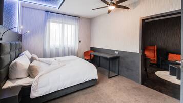 A modern hotel room with a bed, desk, and seating area.