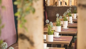 Interior de restaurante con decoración de abedules, macetas blancas con plantas y mesas de madera.