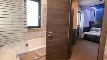 Ein modernes Badezimmer mit einer Badewanne, einer Toilette und einem Fenster mit Jalousien.