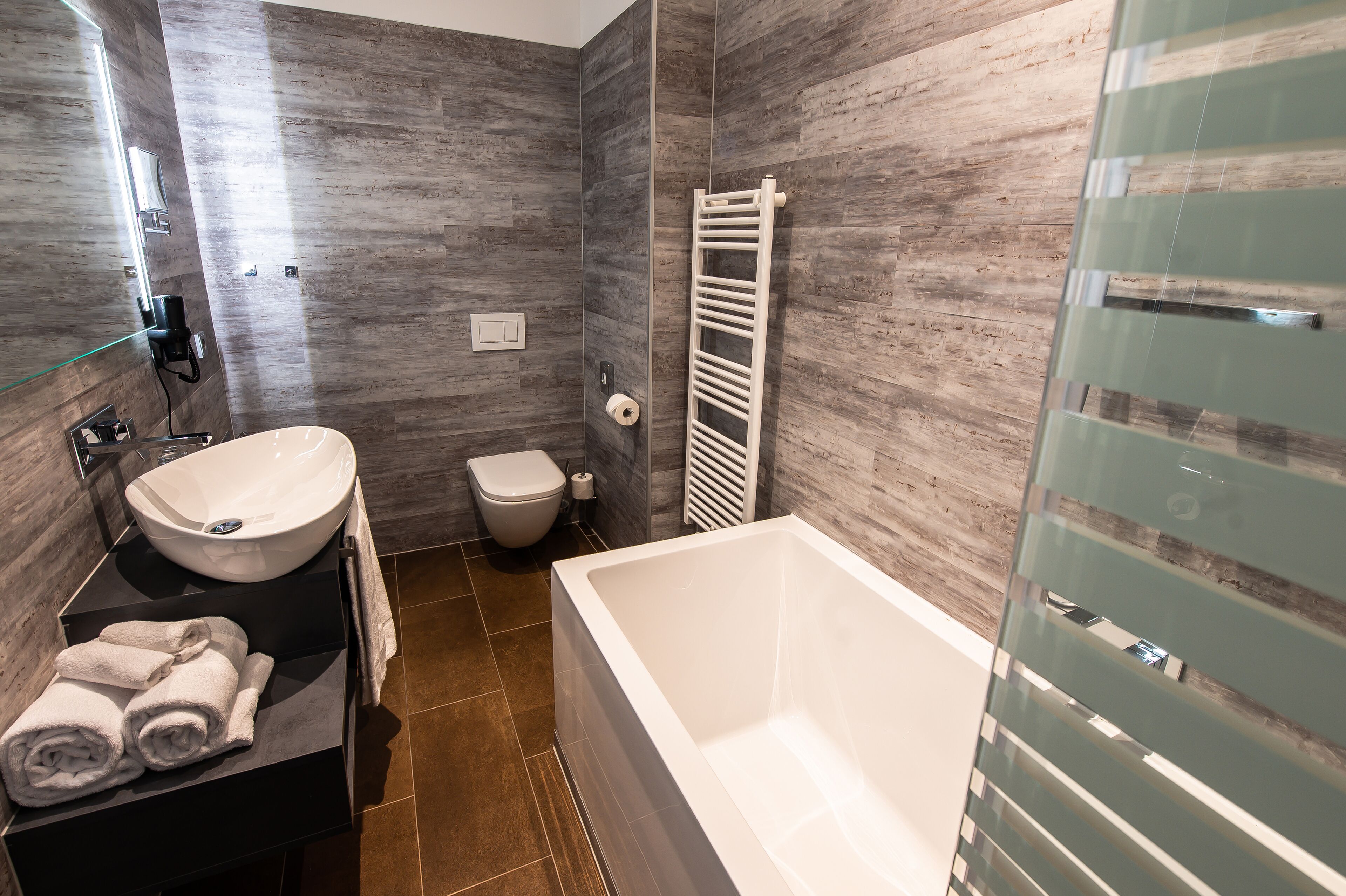 Un baño moderno con una bañera grande, un lavabo y un inodoro.