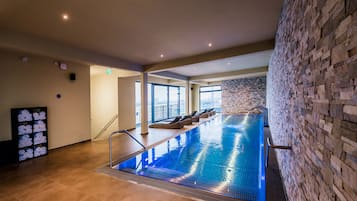 Ein Hallenbad mit Steinwand, einer langen Sitzbank und Fliesenboden.