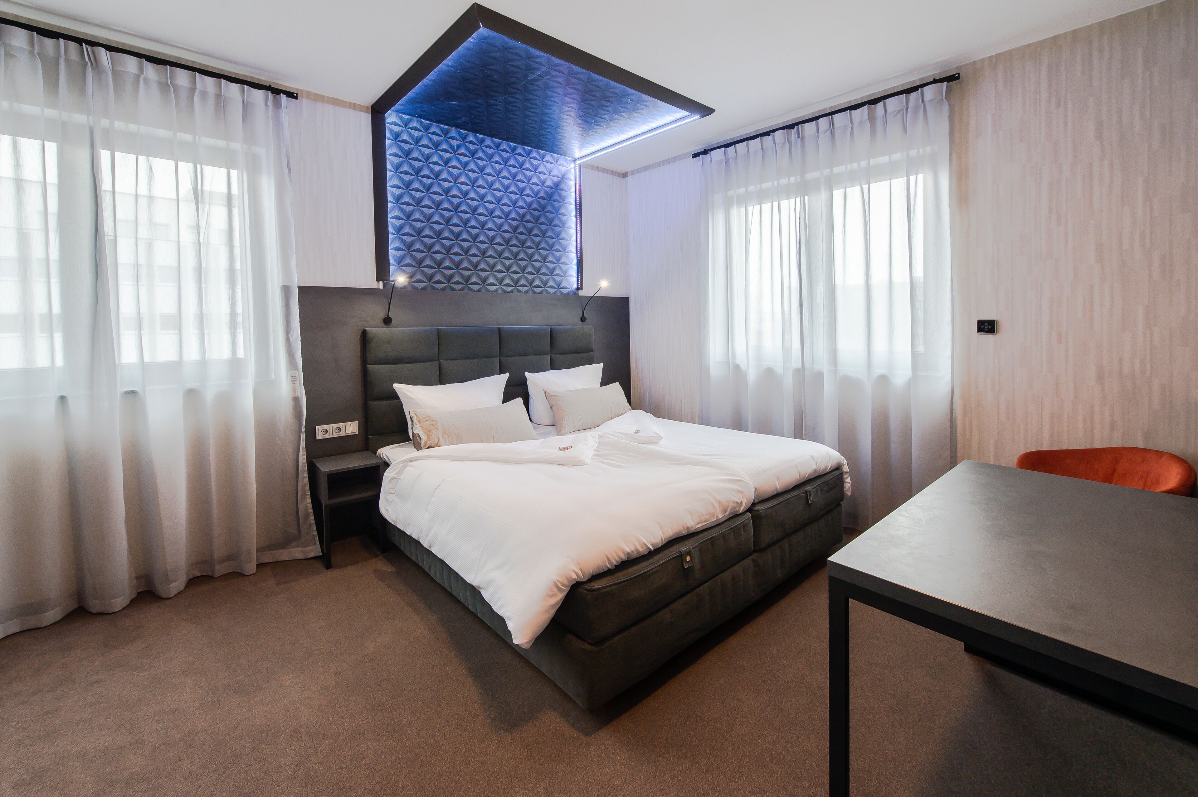 Ein modernes Hotelzimmer mit einem großen Bett, einem Schreibtisch und Blick auf die Stadt.