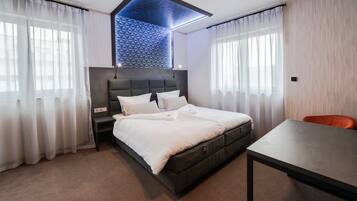 Ein modernes Hotelzimmer mit einem großen Bett, einem Schreibtisch und Blick auf die Stadt.