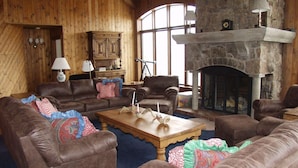 A cozy living room with leather sofas, a wooden coffee table, and a stone fireplace. - Large Family  On Adams Avenue - Ski In/out 5 Bedroom Home by RedAwning (Snowmass Village)