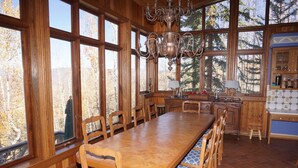 A wooden dining room with a large table and chairs, large windows, and a chandelier. - Large Family  On Adams Avenue - Ski In/out 5 Bedroom Home by RedAwning (Snowmass Village)