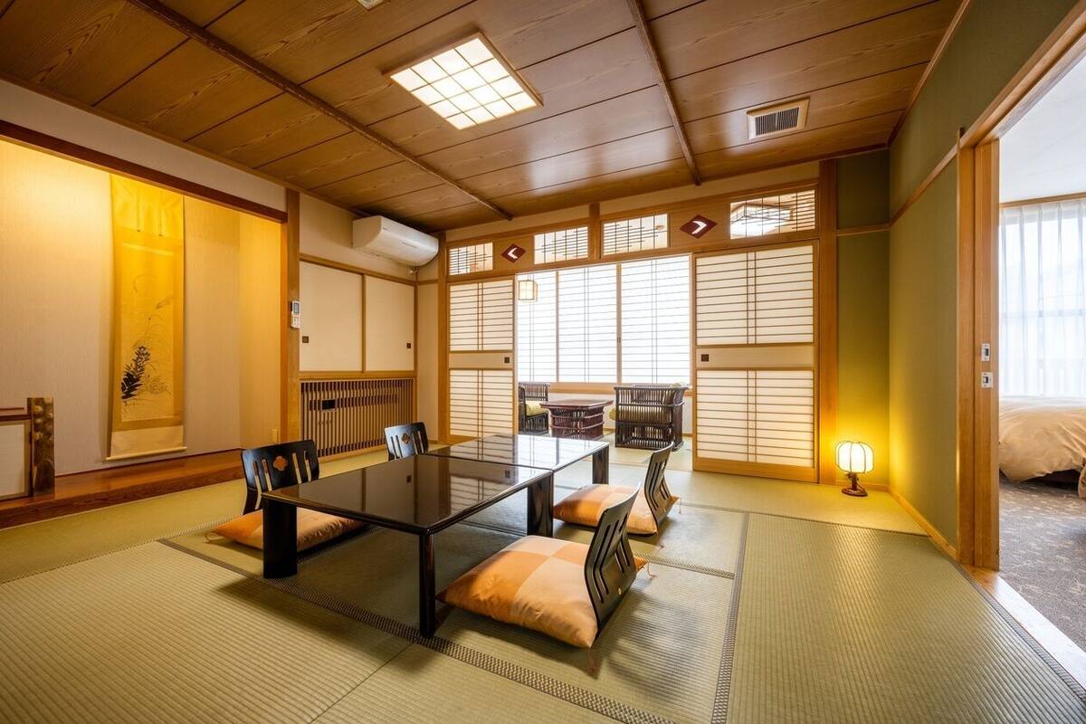 Een traditionele Japanse kamer met tatami vloerbedekking, een lage tafel, stoelen en schuifdeuren.
