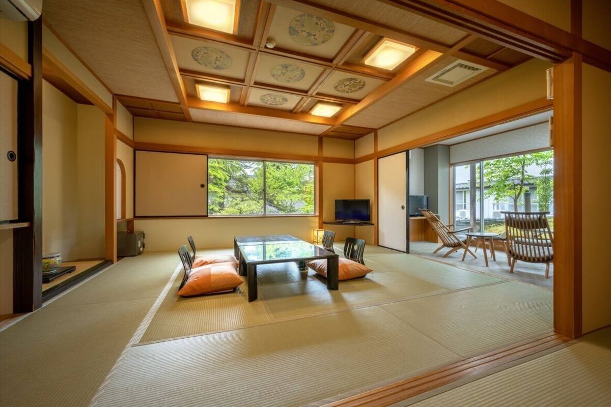 Een traditionele Japanse kamer met tatami vloerbedekking, een lage tafel, kussens en een televisie.