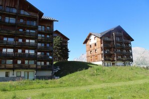Ein mehrstöckiges Holzgebäude mit Balkonen vor einer Bergkulisse.