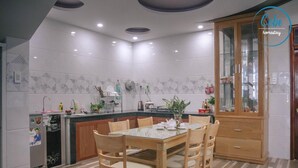 Una cocina moderna con comedor, que incluye una mesa y sillas de madera, un mueble con puertas de cristal y un salpicadero de azulejos.