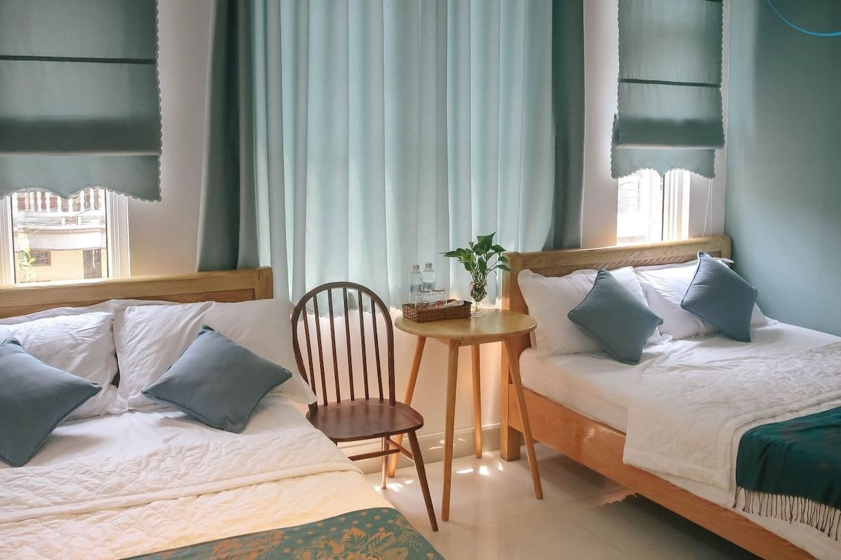 A hotel room with two beds, a small round table, and a chair.
