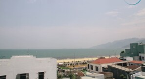 A coastal cityscape with buildings, a beach, and mountains in the distance. - Sông Suối homestay (Quy Nhon)