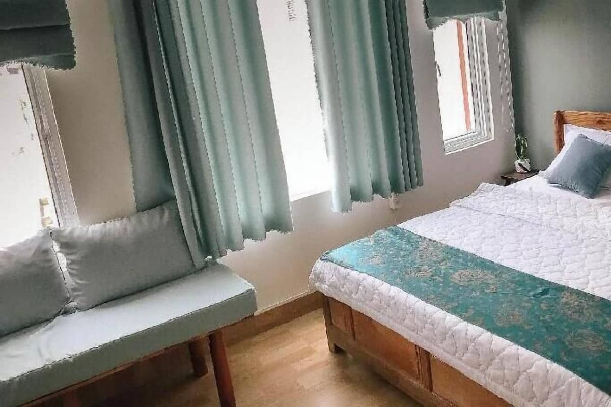 A bedroom with a bed, a bench, and curtains.