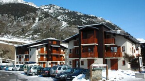 A multi-story hotel with balconies, a parking lot, and a sign indicating a camping area. - Ground floor, balcony, tv, ski locker, 43m², Val Cenis (Lanslevillard)