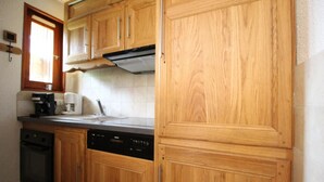 A kitchen with wooden cabinets, a dishwasher, and a coffee maker. - Ground floor, balcony, tv, ski locker, 43m², Val Cenis (Lanslevillard)