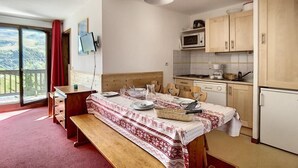 A kitchen with a dining table set for four, a microwave, and a refrigerator. - 100m from ski lifts, 3rd floor, balcony, tv, ski locker, 30m², Les Menuires (Les Menuires)