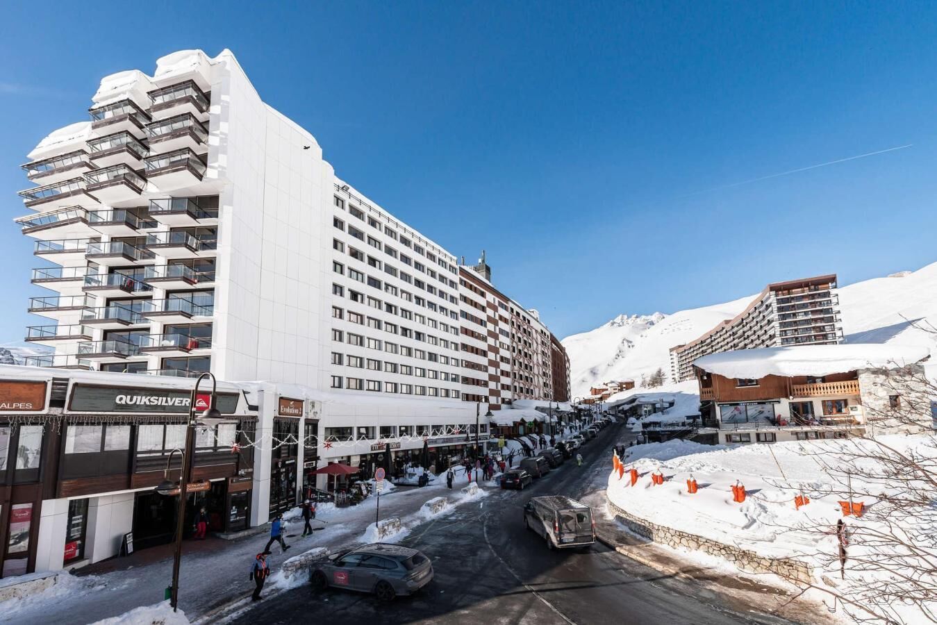 A multi-story hotel with balconies, a snow-covered street, and a clear sky.