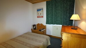 Una habitación pequeña y acogedora con una cama individual, un escritorio de madera y un radiador.