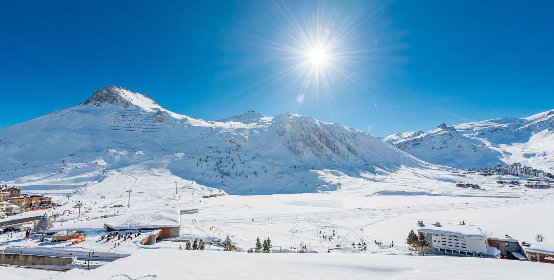 Une montagne enneigée abritant une station de ski, avec des bâtiments et des pistes de ski.