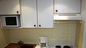 Una cocina con armarios blancos, un microondas, una cafetera y una estufa.