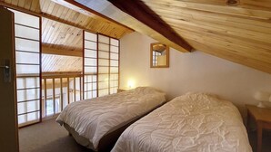 Ein Zimmer mit zwei Betten, Holzboden und einer Schiebetür mit satinierten Glasscheiben.