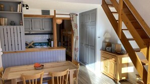 A cozy kitchen with wooden furniture, a dining table, and a staircase. - 4th floor, swimming pool, balcony, tv, ski locker, 46m², Valloire (Valloire)
