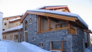 Un bâtiment en pierre doté d’un balcon en bois, entouré de neige.