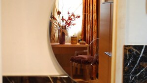 A circular mirror reflecting a room with a desk, chair, and decorative vase. - Residenza San Faustino (Verona)