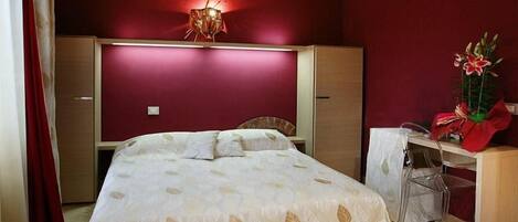 A bedroom with a bed, a desk, and a chair.