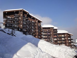 Ein mehrstöckiges Hotel mit Balkonen und verschneiter Landschaft.