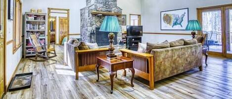A living room with a stone fireplace, a bookshelf, a sofa, and a television.