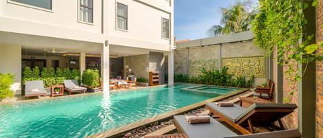 A modern hotel with a rooftop pool area, lounge chairs, and a dining setup.