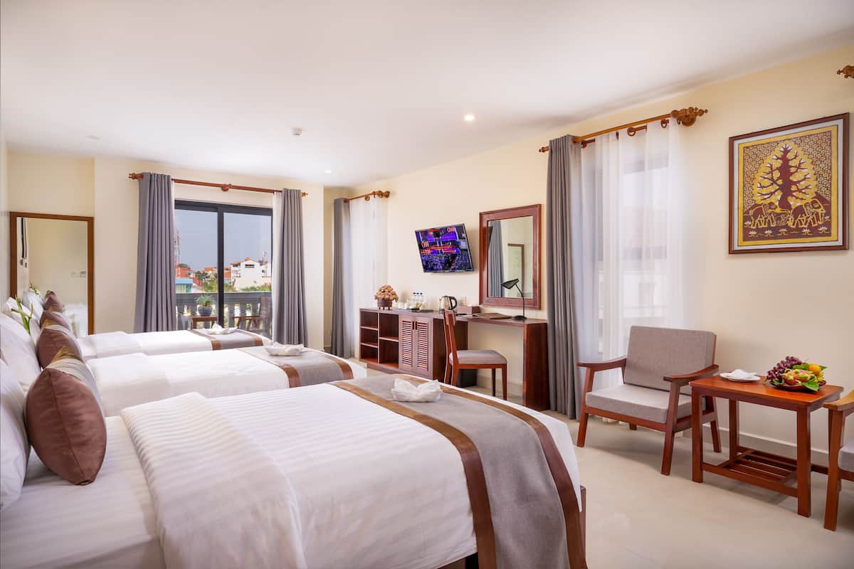 A hotel room with two beds, a desk, a chair, a TV, and a large window with curtains.