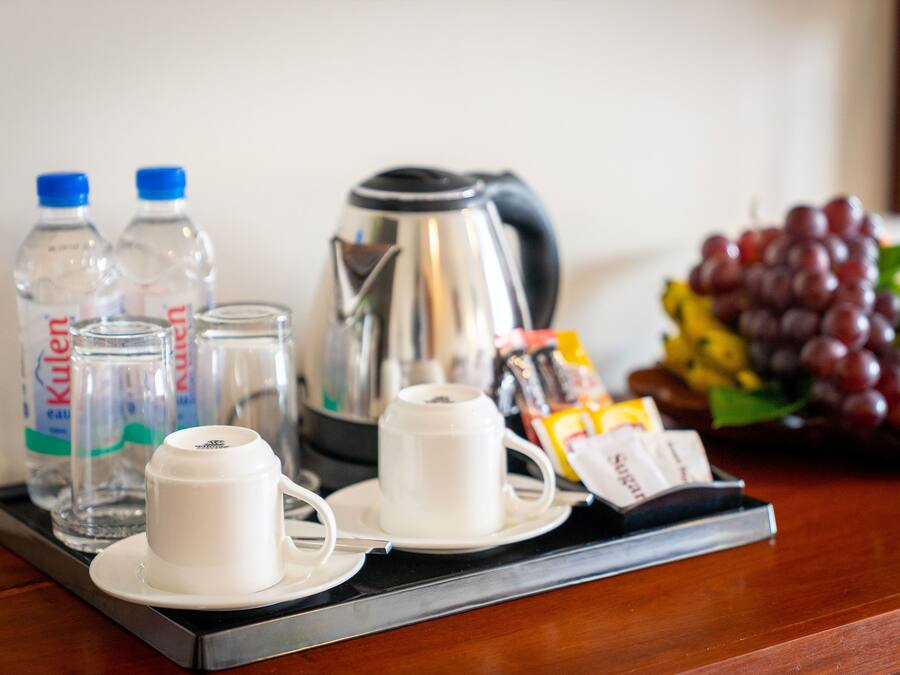 A tray with a coffee maker, two cups, two bottles of water, a packet of sugar, and a bunch of grapes.