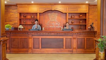 Una recepción con dos empleados, paneles de madera y elementos decorativos.