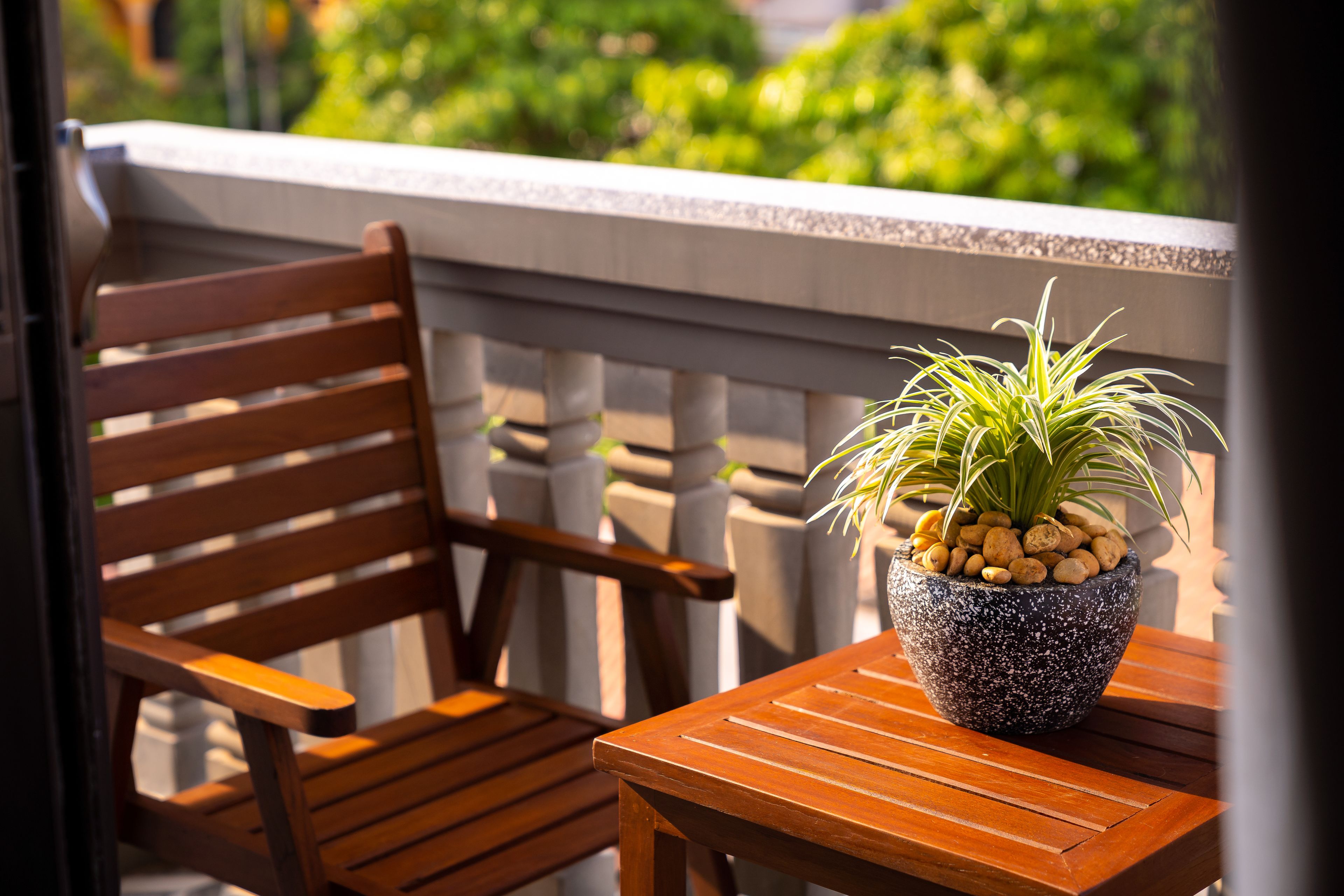A wooden chair and table with a potted plant on a balcony.