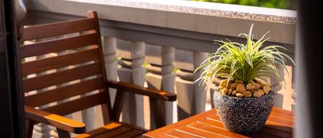 A wooden chair and table with a potted plant on a balcony.