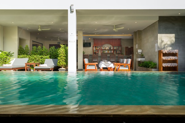 Una piscina al aire libre, sombrillas, sillones reclinables de piscina