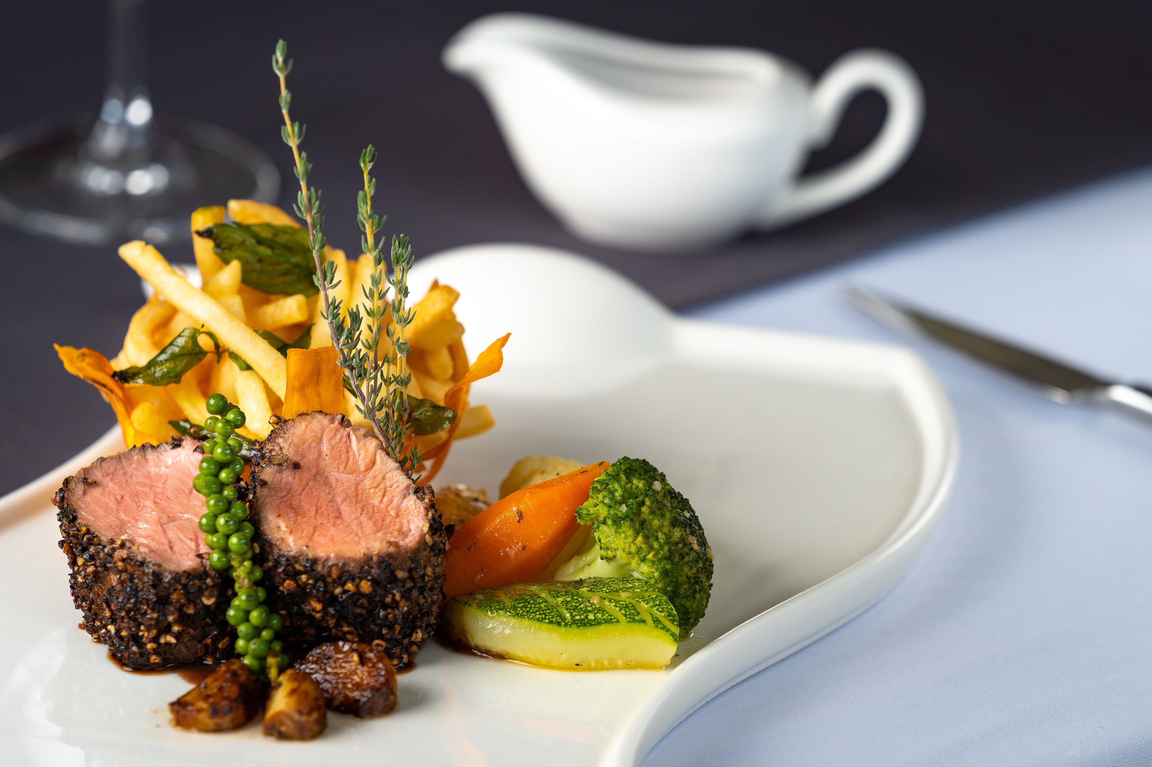 A plated meal with steak, vegetables, and a small bowl of sauce.